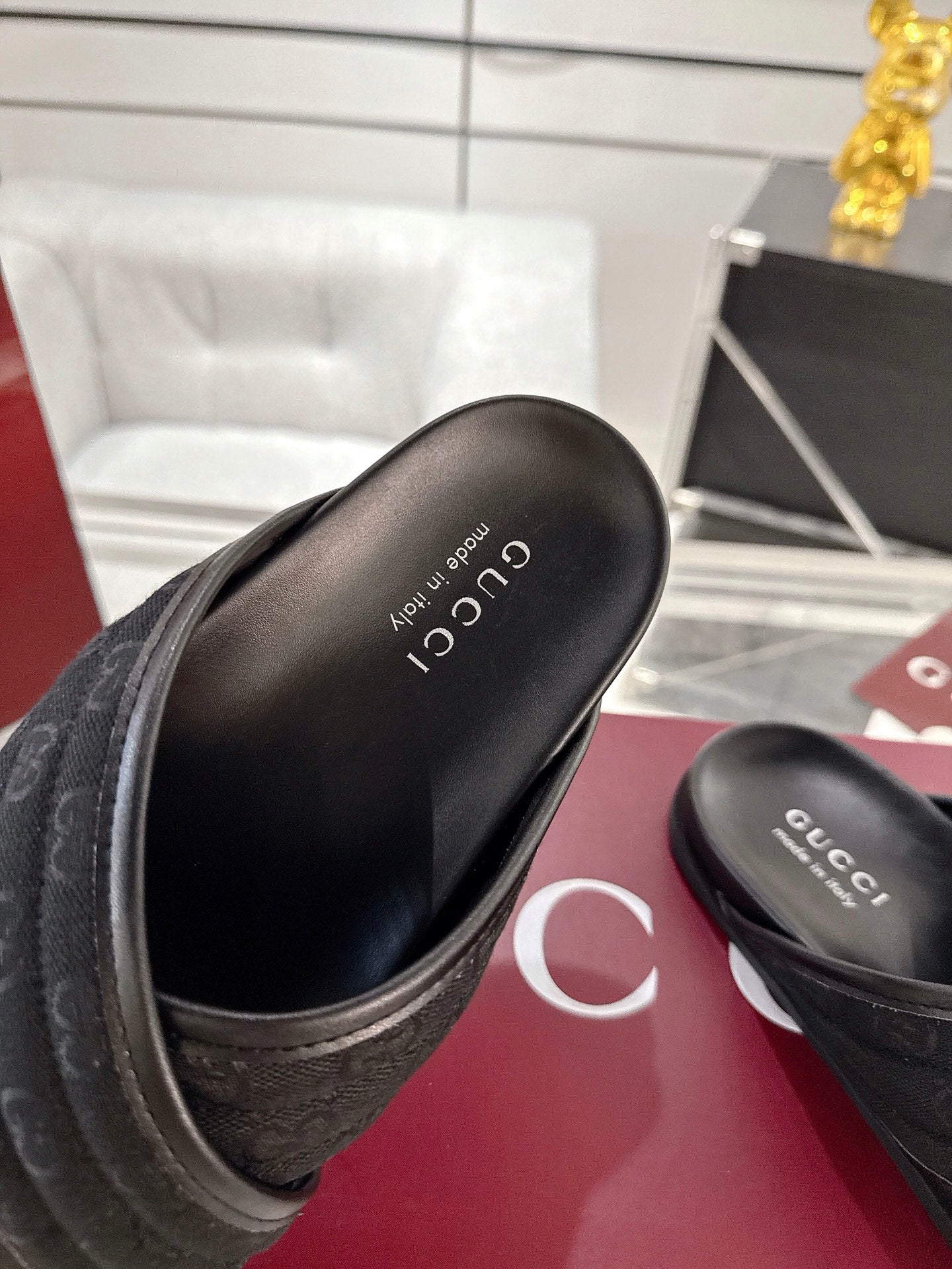 Black Gucci slide sandals close-up of insole with printed Gucci logo.