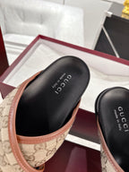 Gucci slide sandals close-up, black footbed with text and beige GG canvas strap