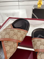 Gucci slide sandals close-up: beige GG canvas strap with tan trim, black footbed