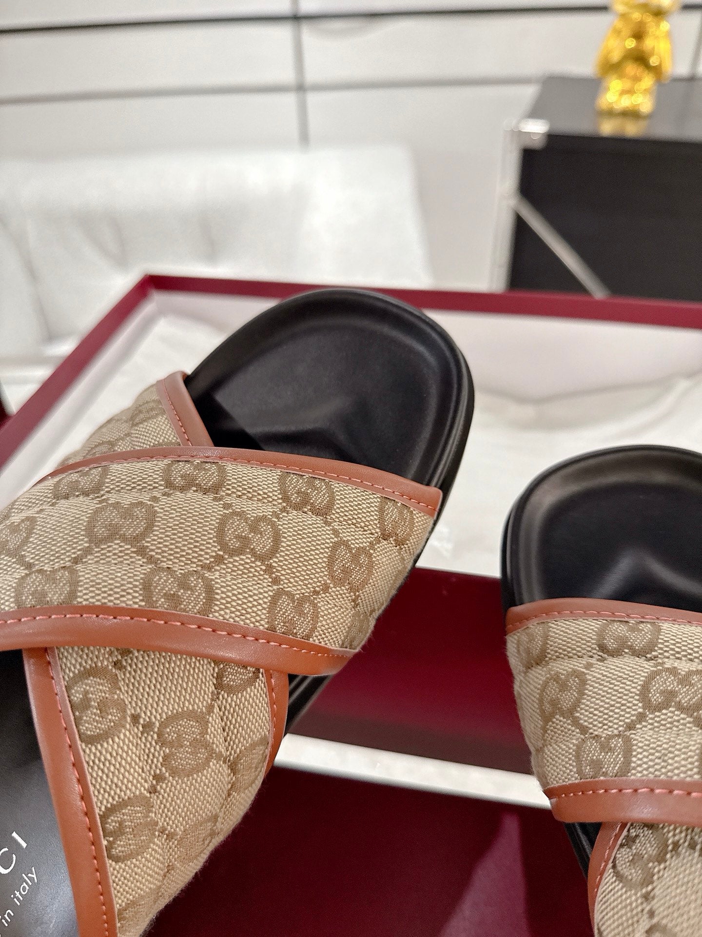 Gucci slide sandals close-up: beige GG canvas strap with tan trim, black footbed