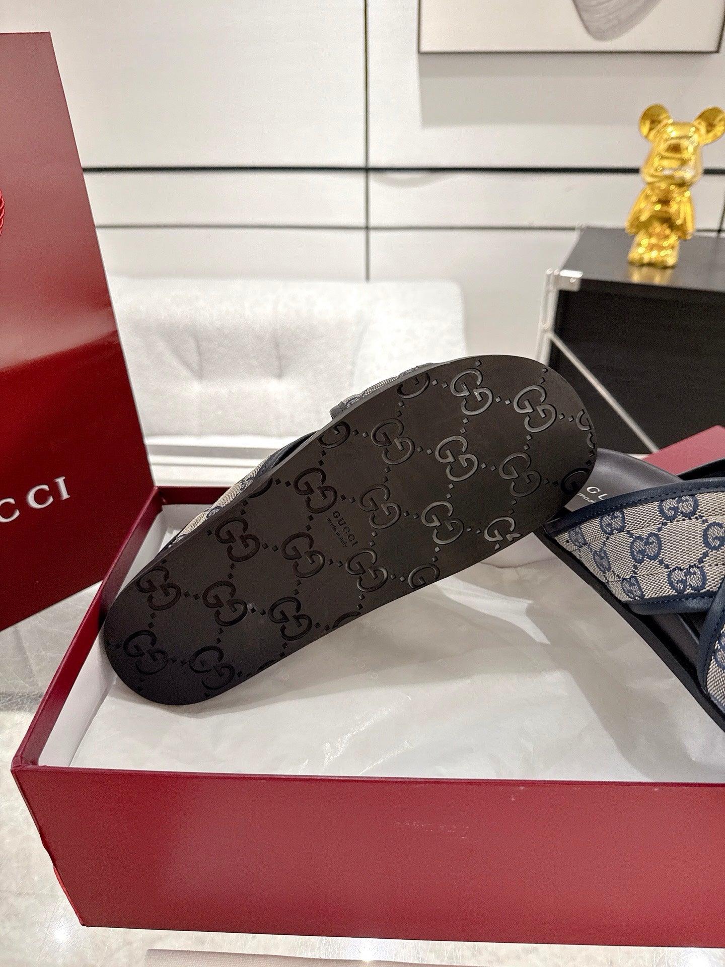 Gucci slide sandals with dark GG-pattern strap and black rubber sole