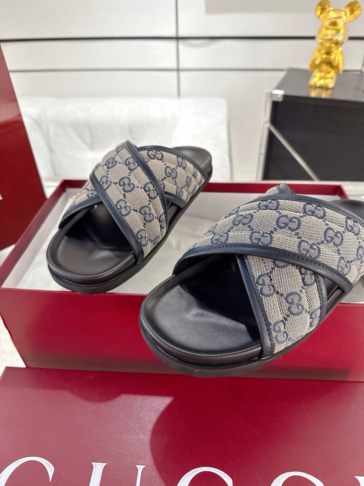Gucci slide sandals with blue GG canvas straps and black soles, side view
