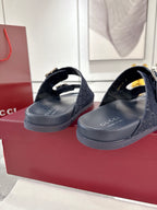 Navy Gucci slide sandals with silver buckles and GG monogram straps, angled