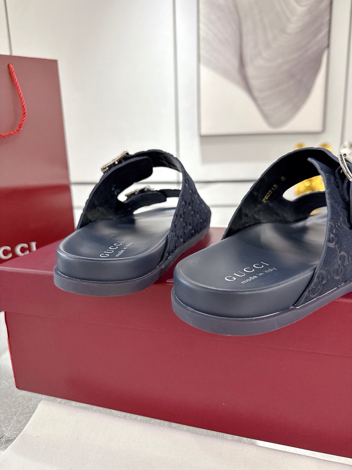Navy Gucci slide sandals with silver buckles and GG monogram straps, angled