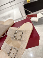 Gucci monogram slide sandal close-up: two silver-tone buckle straps on beige