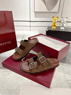 Brown logo-print slide sandals with two silver-tone buckles, worn in a side view