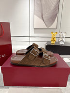 Brown logo-print slide sandals on display box, featuring two silver-tone buckle straps