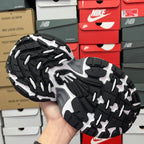 Unisex sneaker outsole view with black tread and white sculpted midsole.