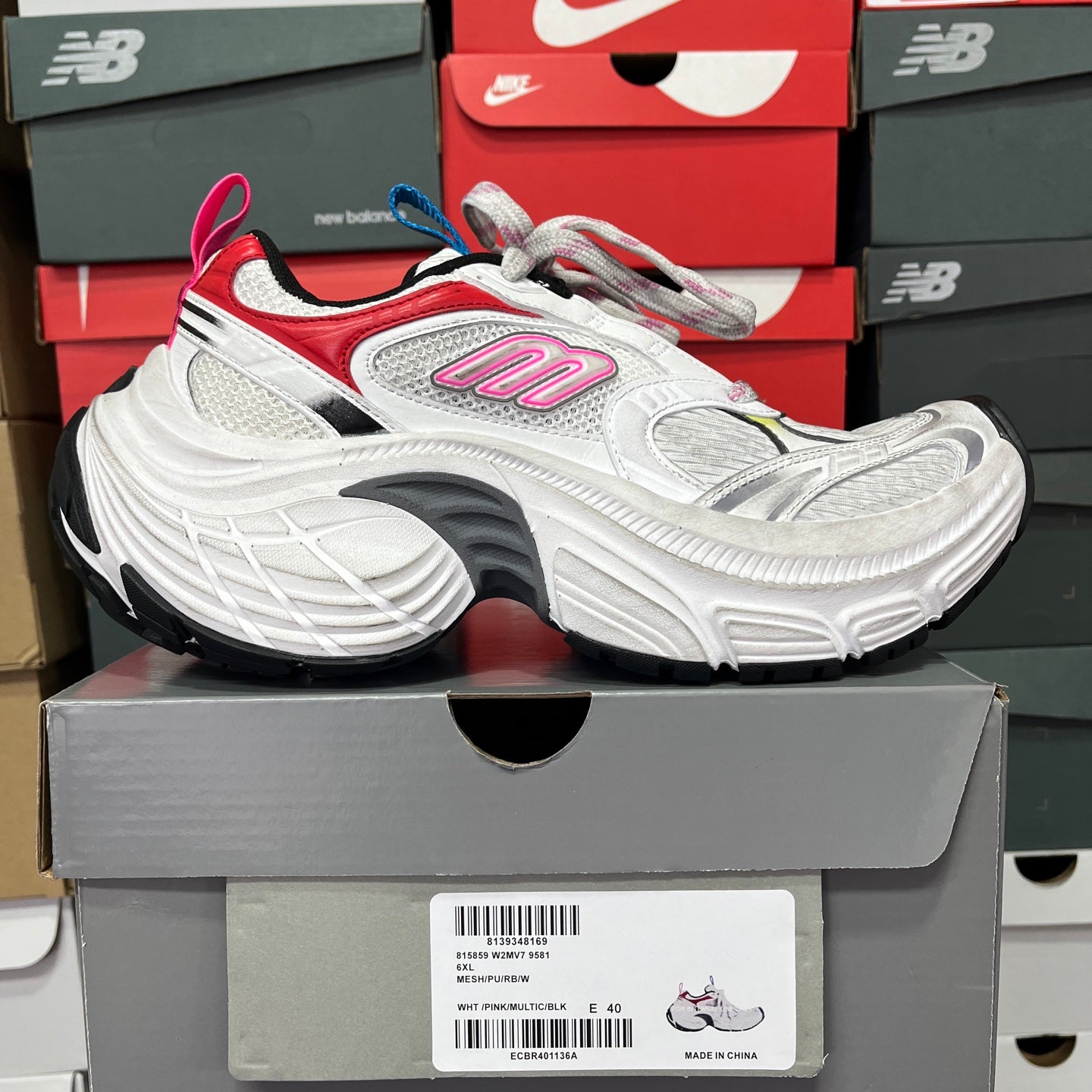 Unisex sneaker with white upper, red side panel, and blue trim around heel.