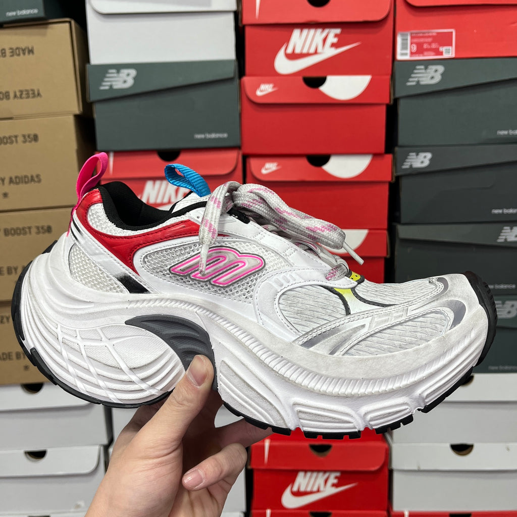 Unisex sneaker with white upper, red accents, and multicolor lace eyelets.