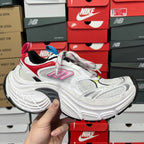 Unisex sneaker with white upper, red accents, and multicolor lace eyelets.