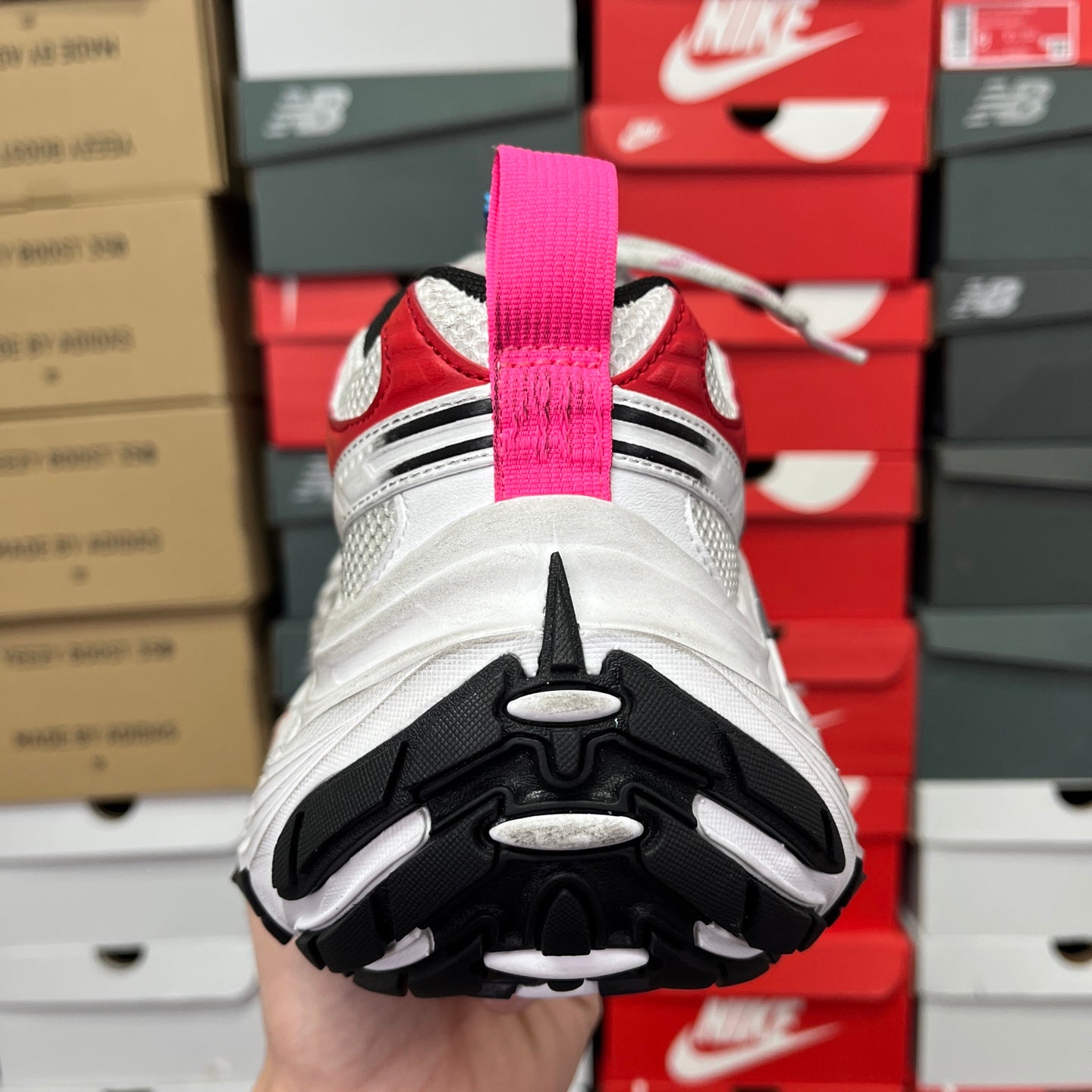 Unisex sneaker outsole and heel view with black traction pods and white cushioning.