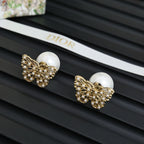 Gold butterfly stud earrings with white pearl centers and crystal detailing