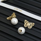 Gold butterfly earrings with white pearl studs and sculpted filigree