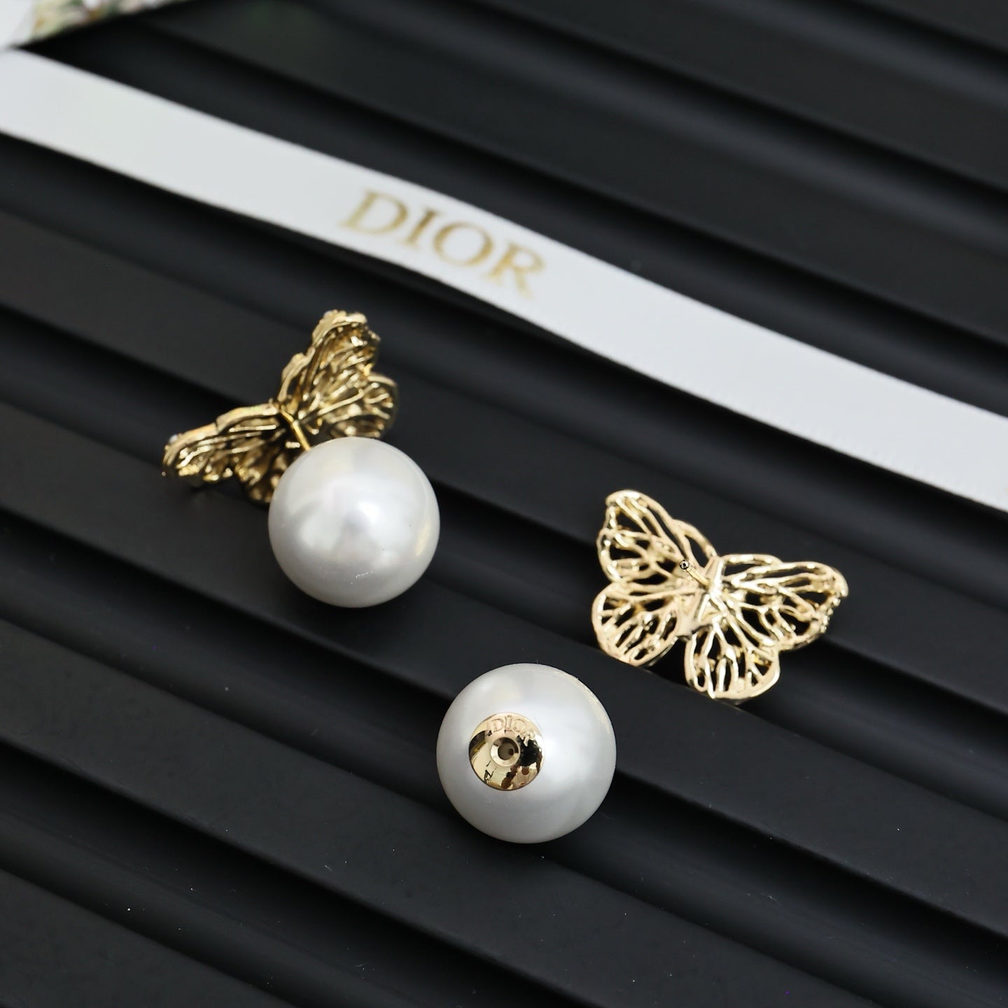 Gold butterfly earrings with white pearl studs and sculpted filigree