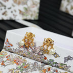 Dior gold-tone earrings with pearls and star charms on floral display