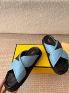 Light blue slide sandals with black soles and crisscross strap design