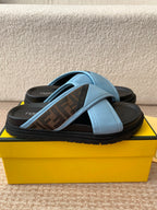 Light blue slide sandals with cross strap over dark printed footbed