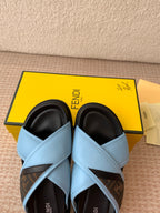 Light blue slide sandals with black interior lining and crisscross straps
