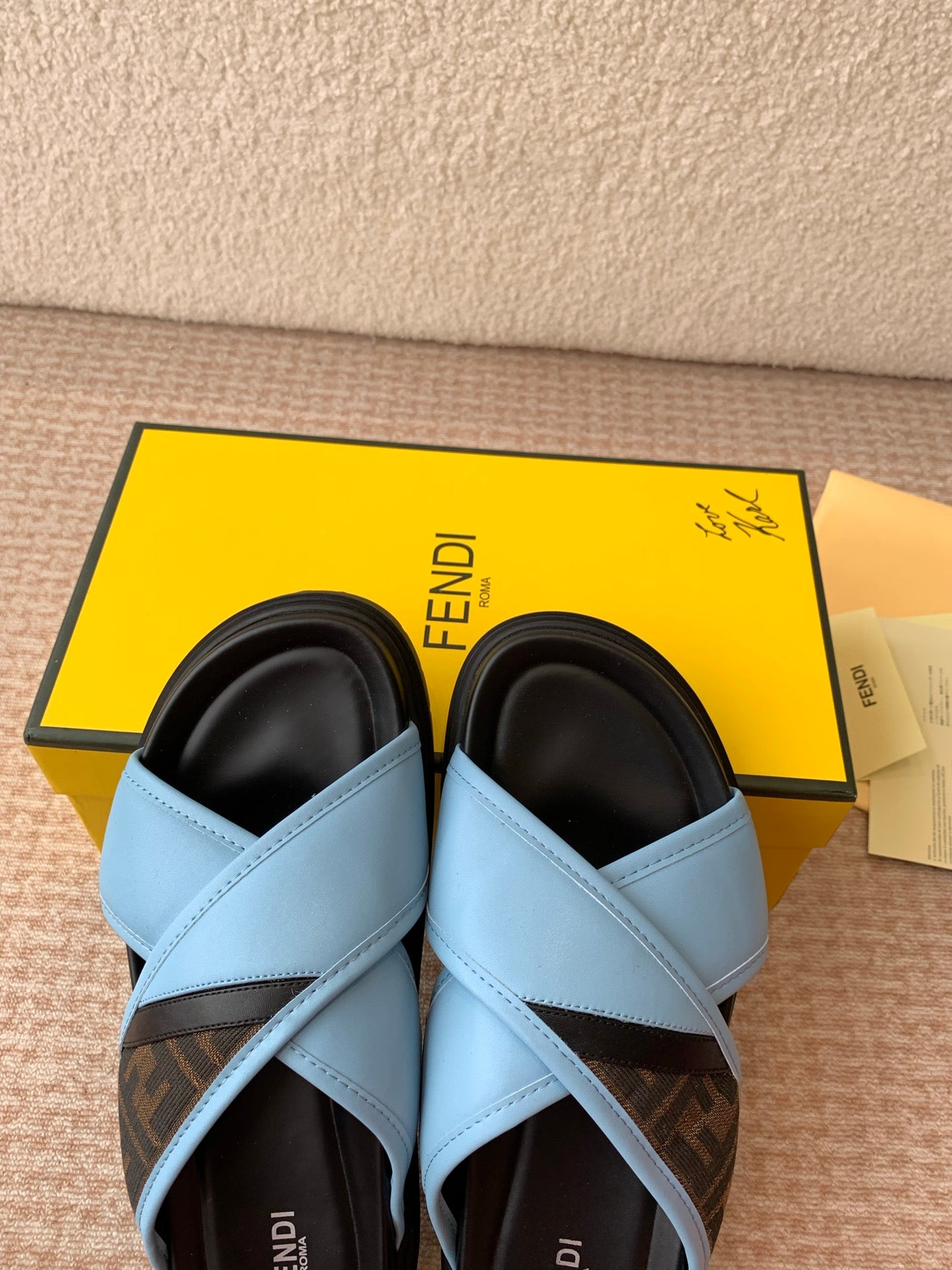 Light blue slide sandals with black interior lining and crisscross straps