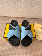 Fendi light blue slide sandals with crisscross straps and black rubber soles