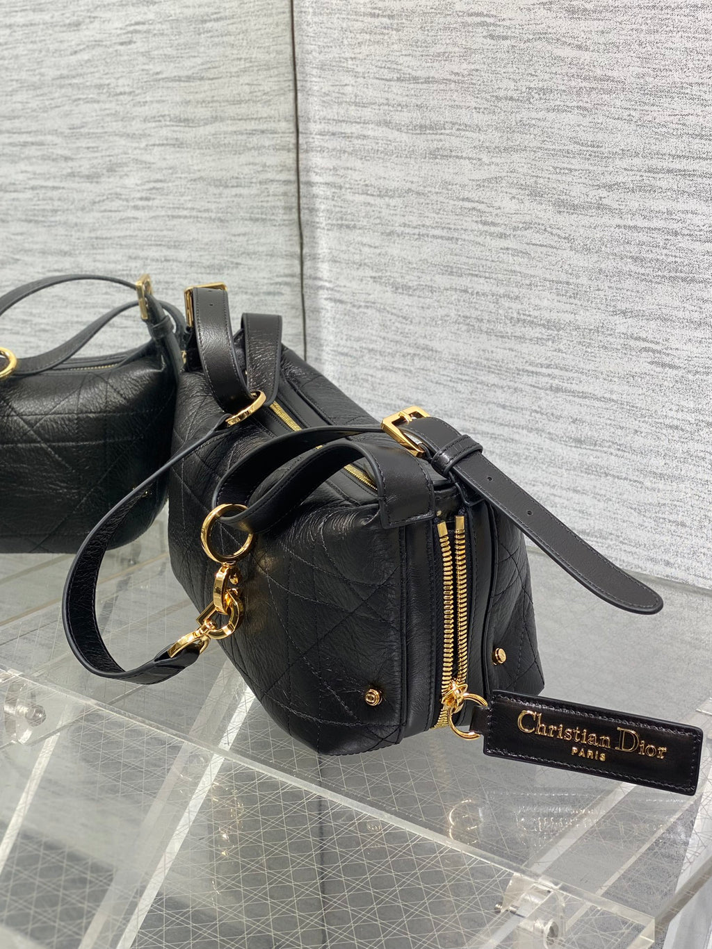 Black Dior small satchel with gold zipper, chain strap, and logo charm