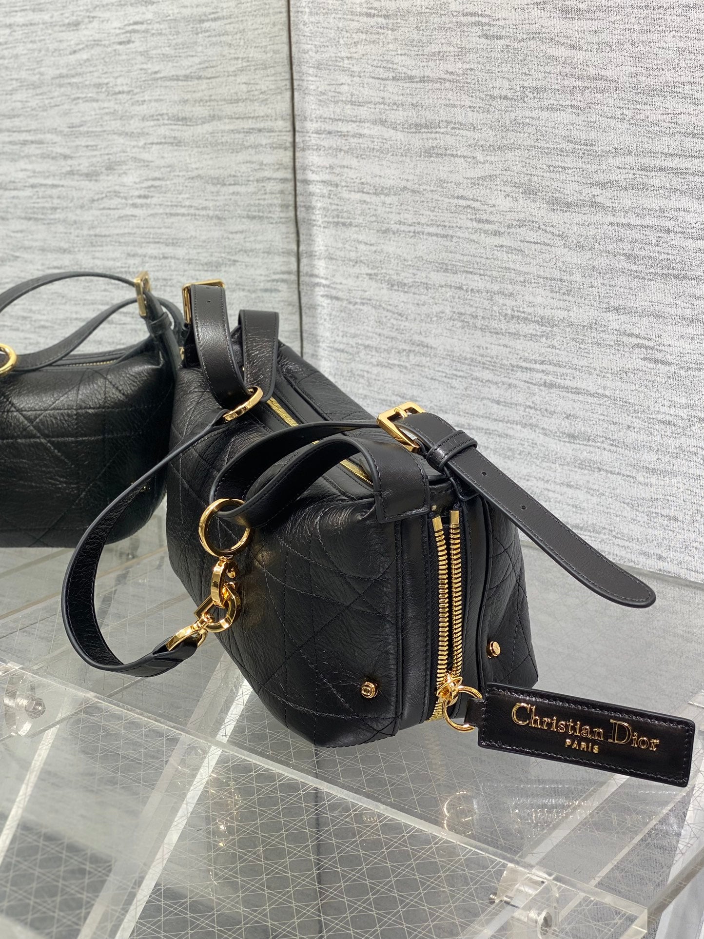 Black Dior small satchel with gold zipper, chain strap, and logo charm