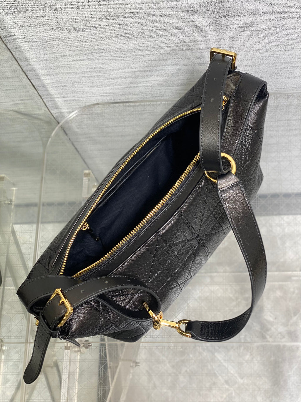 Black Dior crossbody bag with open top, gold zipper, and adjustable strap
