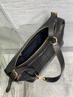 Black Dior crossbody bag with open top, gold zipper, and adjustable strap