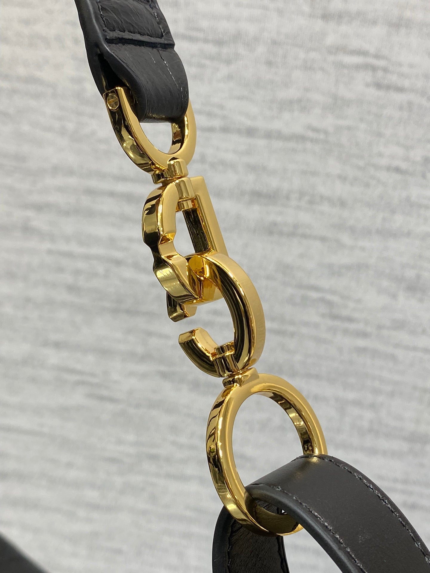 Gold-tone Dior clasp hardware on black strap with rounded link detail