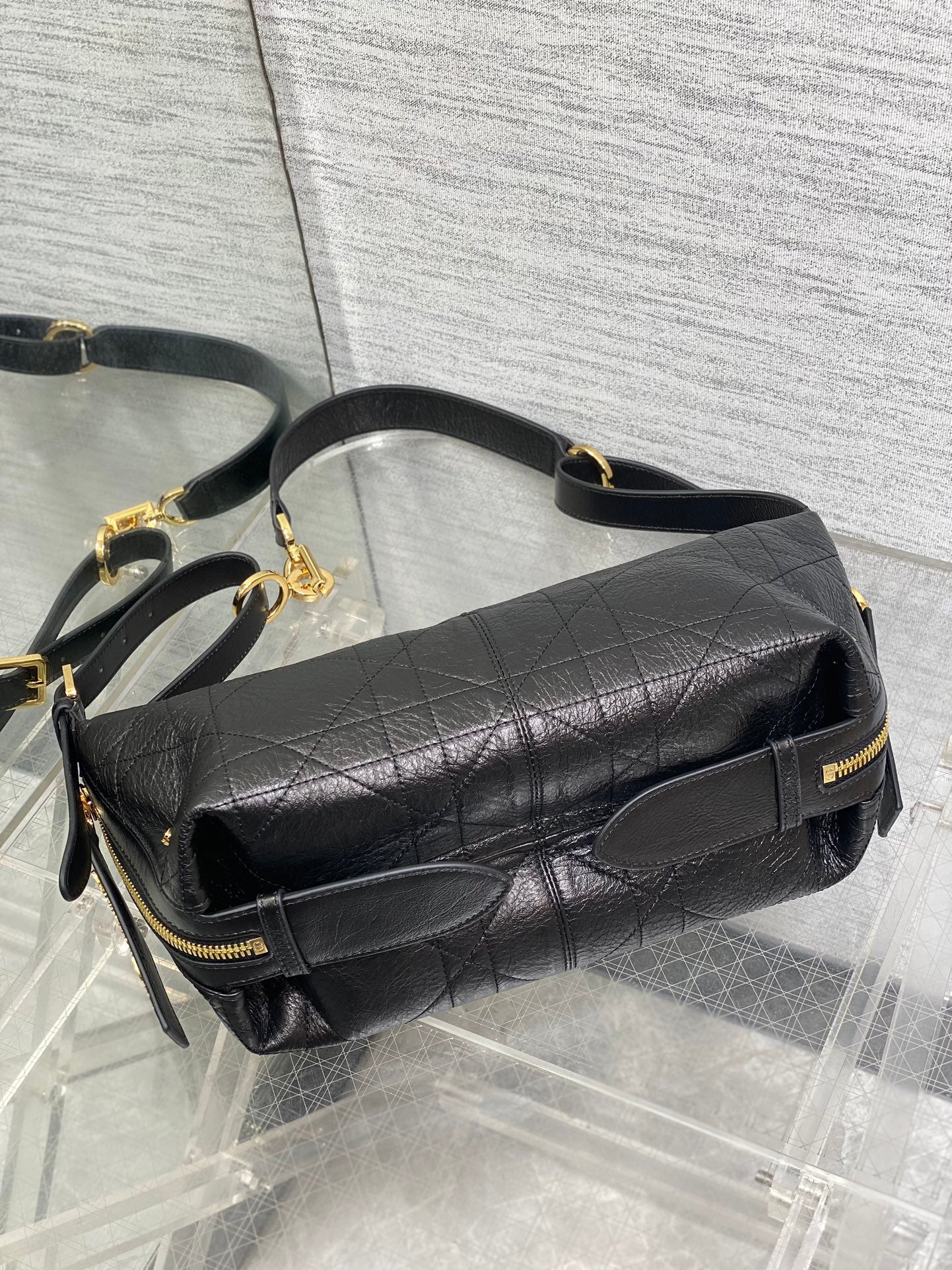 Black Dior leather crossbody bag with flap, gold-tone zipper, and chain strap