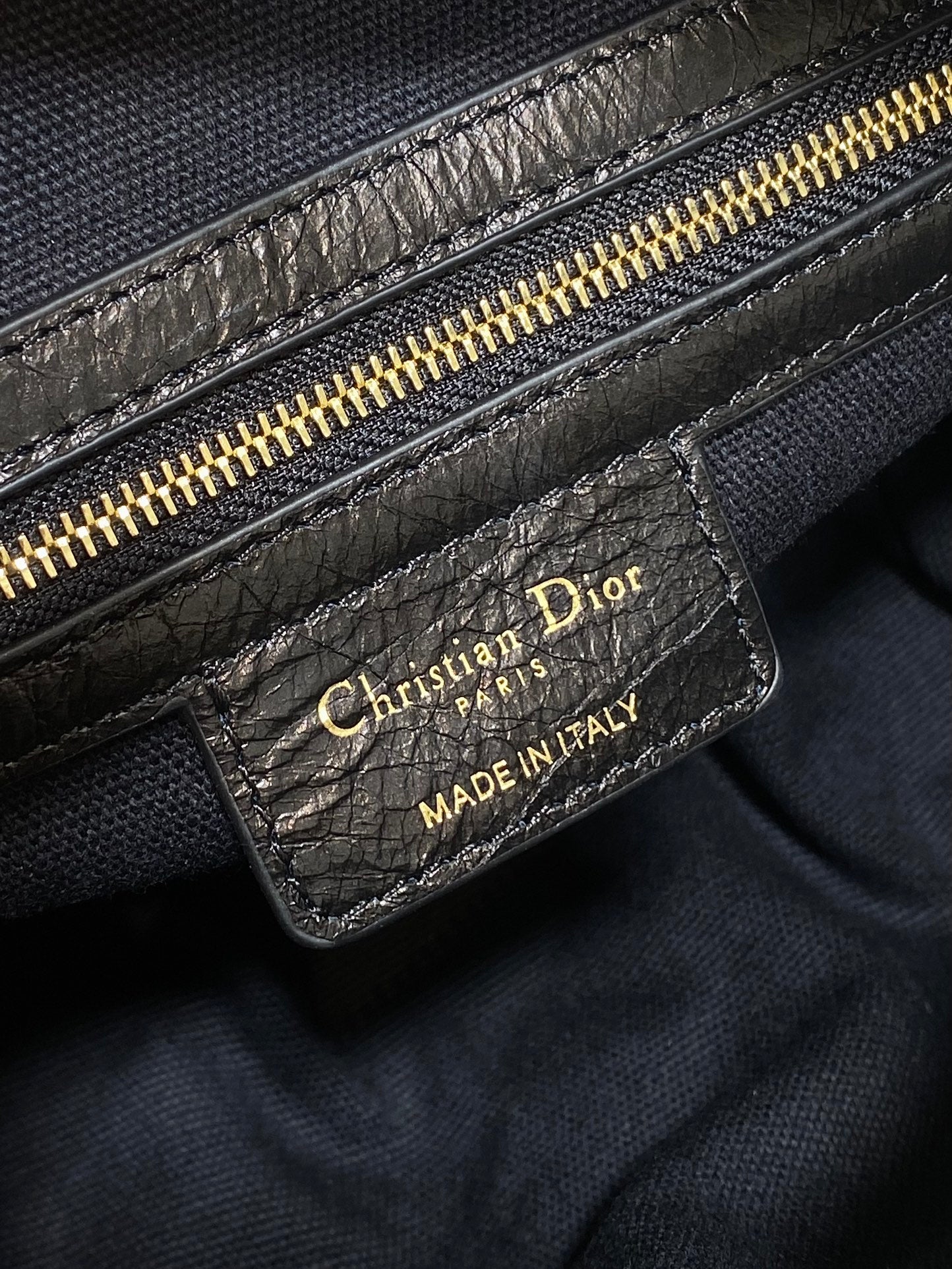 Black Dior leather bag with gold zipper and 'Made in Italy' logo patch