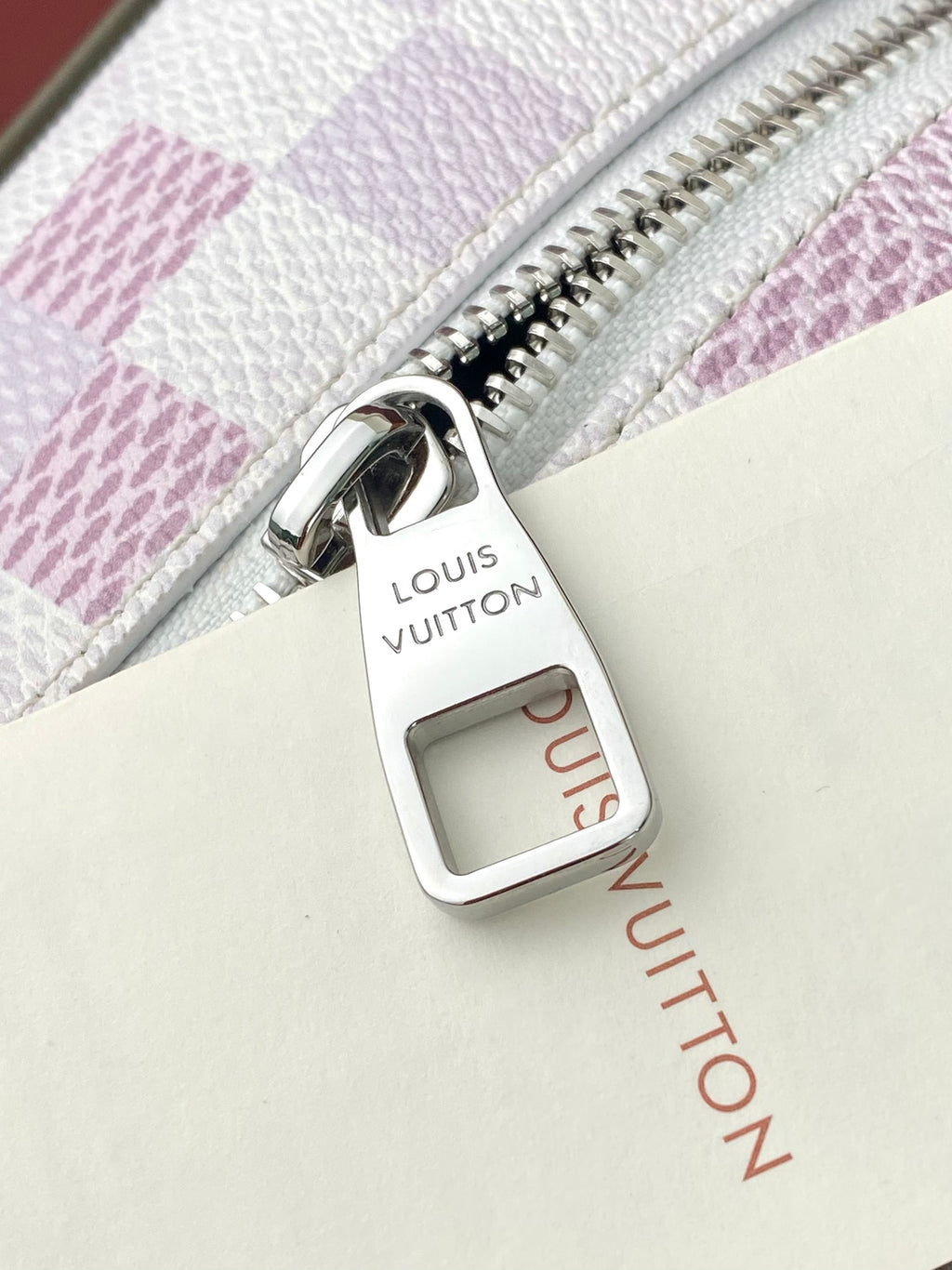 Louis Vuitton zipper pull with leather tab marked Louis Vuitton on check bag