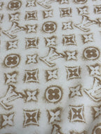Cream T-shirt fabric with repeating gold monogram icons.