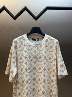 Cream short-sleeve T-shirt with gold monogram pattern, crew neckline detail.