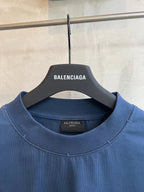 Blue crewneck T-shirt close-up, ribbed neckline and Balenciaga label at collar.
