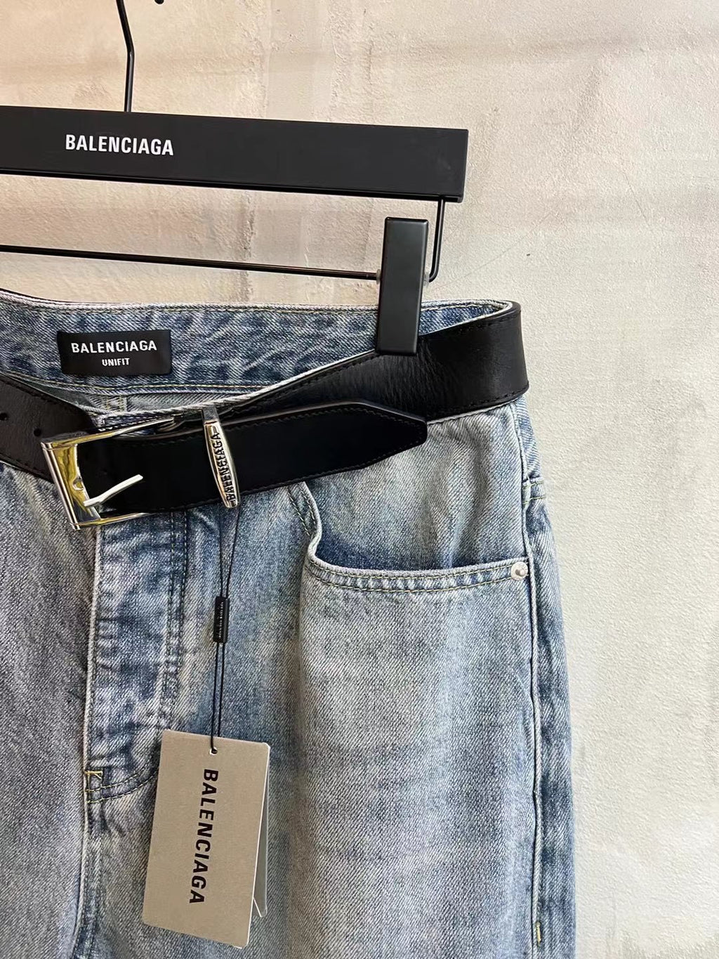 Light blue denim pants with black leather belt and button fly