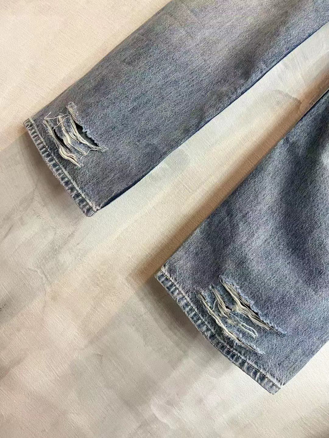 Light blue denim pants laid flat, showing knee rips and frayed hems