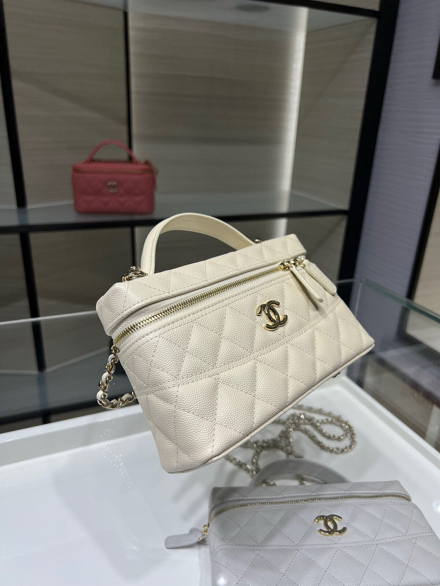 Mini quilted white Chanel bag with top handle, zipper, and chain strap
