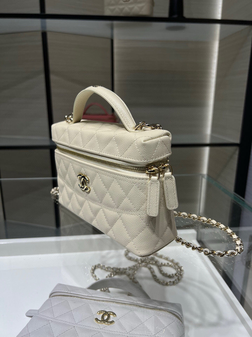 Small quilted white Chanel handbag with gold logo, zipper, and chain strap