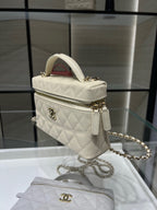 Small quilted white Chanel handbag with gold logo, zipper, and chain strap