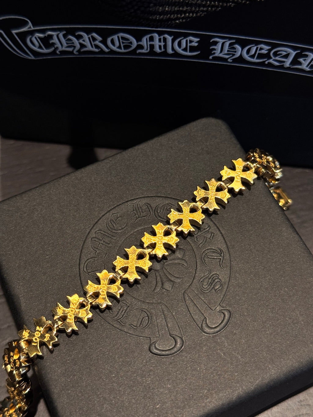 Gold-tone bracelet with teal-green stones and gold cross-shaped links
