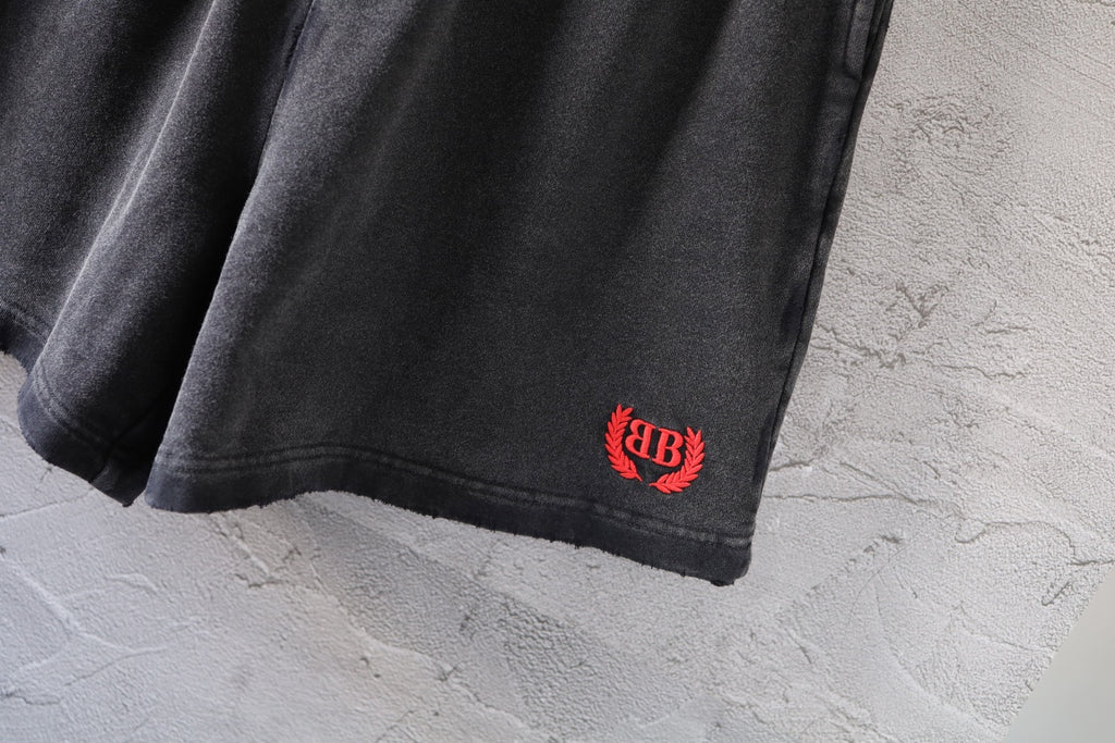 Dark gray denim shorts hem with small red and black logo patch