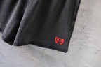 Dark gray denim shorts hem with small red and black logo patch