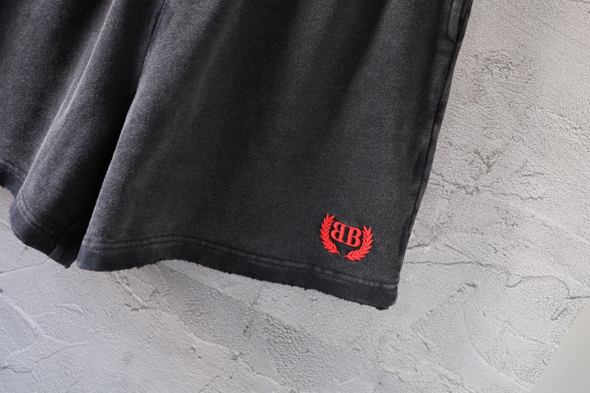 Dark gray denim shorts hem with small red and black logo patch