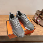 Gray suede lace-up sneakers pair on display, white ridged soles, low-top design