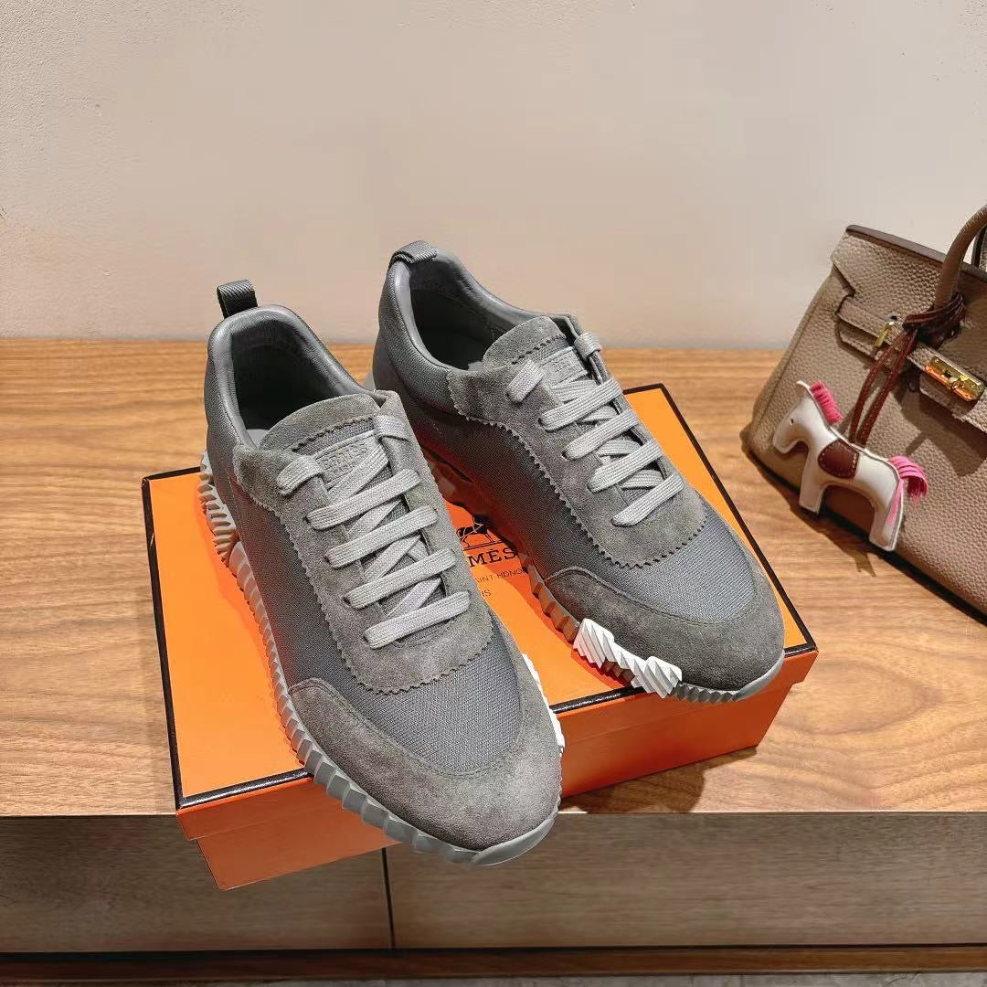 Gray suede lace-up sneakers pair on display, white ridged soles, low-top design
