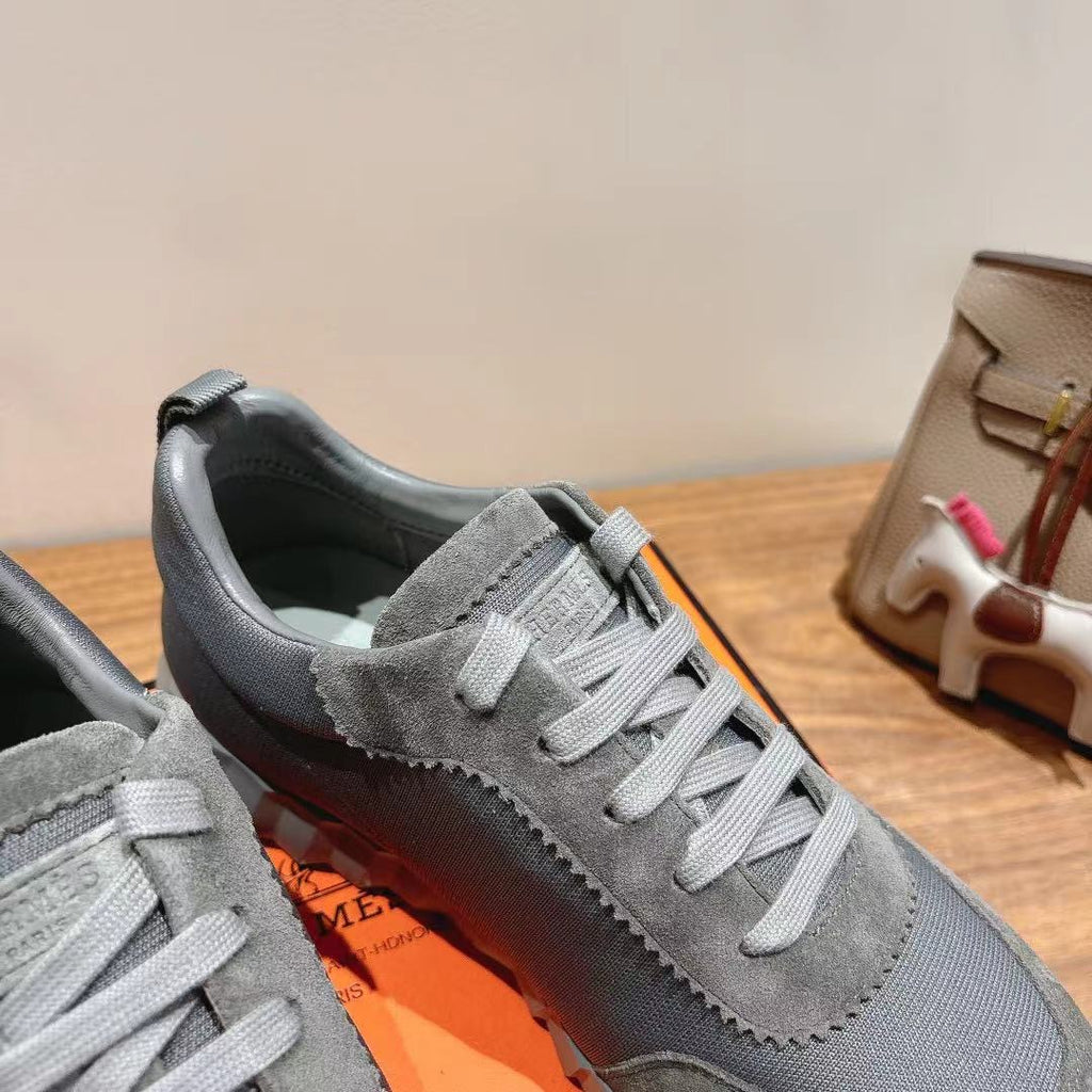 Gray suede lace-up sneaker close-up, white laces, stitched trim and dark heel