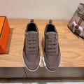 Grey suede lace-up sneakers with white ridged sole, Hermes branding on heel