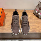 Grey suede lace-up sneakers with white ridged sole, Hermes branding on heel